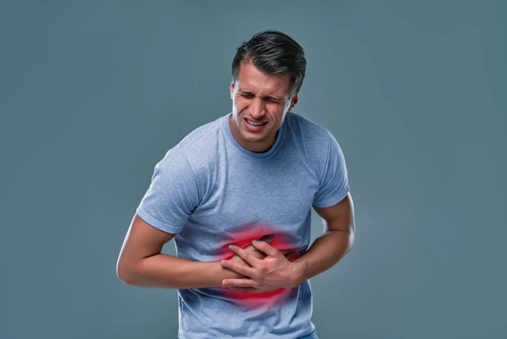 man white t shirt with stomachache gray room scaled 1 - Laparoscopic Surgeon Dr. Digant Pathak